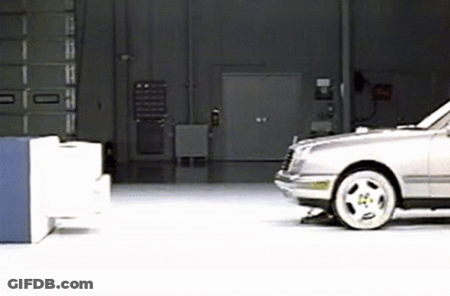 A Silver Car Is Parked In A Garage In Front Of A Door . GIF