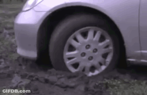 A Silver Car Is Stuck In A Muddy Area . GIF