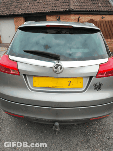 A Silver Car With A Yellow License Plate Number 7 GIF