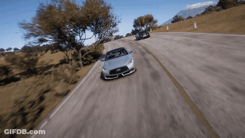 A Silver Infiniti Sports Car Is Driving Down A Road GIF