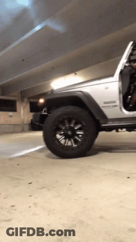 A Silver Jeep Is Parked In A Parking Garage With The Door Open GIF