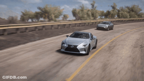 A Silver Lexus Is Driving Down A Road Next To A Silver Car GIF