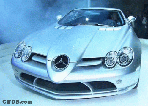 A Silver Sports Car With A Mercedes Logo On It GIF