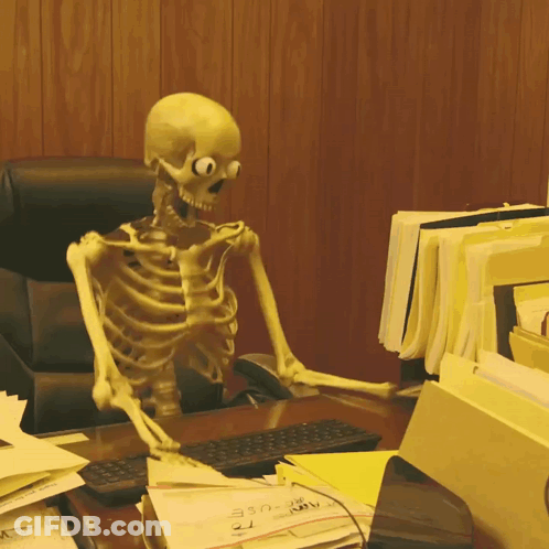 A Skeleton Is Sitting At A Desk With A Bunch Of Papers Including One That Says ' A ' On It GIF