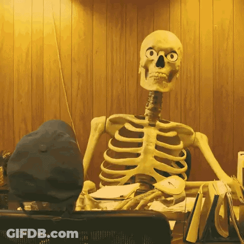 A Skeleton Is Sitting At A Desk With A Hat On GIF