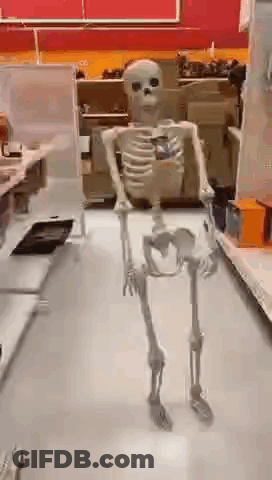 A Skeleton Is Standing In A Store Holding A Cell Phone . GIF