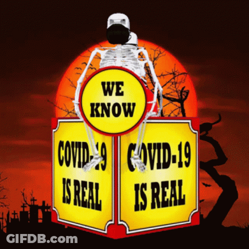 A Skeleton Wearing A Mask Sits On Top Of A Sign That Says We Know Covid-19 Is Real GIF