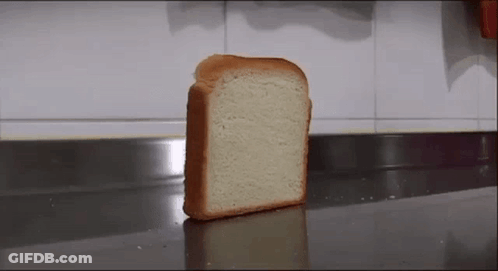 A Slice Of Bread Is Sitting On A Counter In Front Of A Wall . GIF