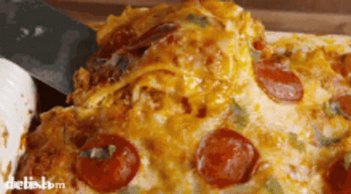 A Slice Of Pepperoni Pizza Is Being Taken Out Of A Casserole Dish GIF