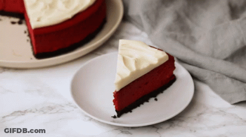 A Slice Of Red Velvet Cheesecake With White Frosting On A Plate GIF