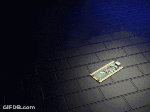 A Small Electronic Device Is Laying On A Black Tiled Floor GIF