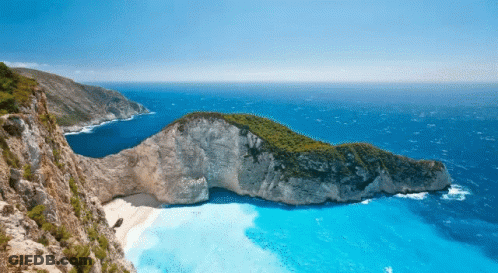 A Small Island In The Middle Of The Ocean With A Boat In The Water GIF