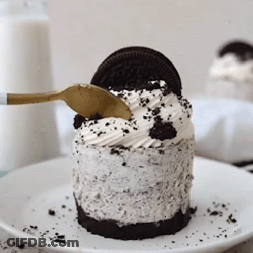 A Small Oreo Cheesecake On A White Plate With A Gold Spoon GIF