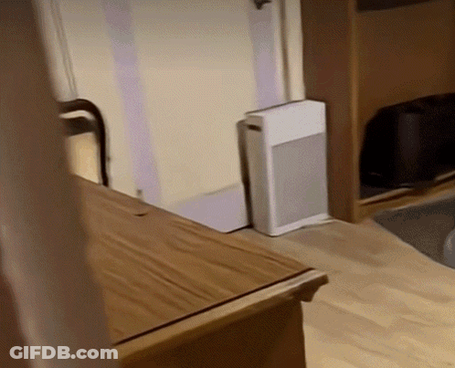 A Small White Box Is Sitting On The Floor Next To A Wooden Table GIF