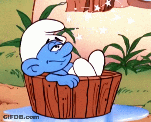 A Smurf Is Sitting In A Wooden Tub With His Feet In The Water GIF