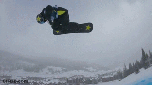 A Snowboarder Is Doing A Trick In The Air With A Star On His Board GIF