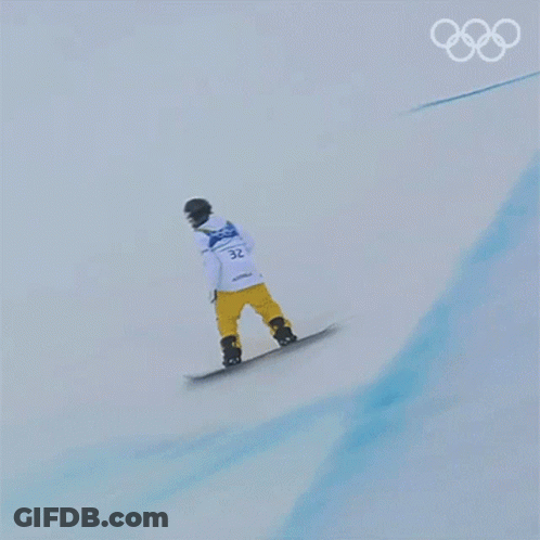 A Snowboarder Is Doing A Trick On A Snowy Slope With The Olympic Rings In The Background GIF