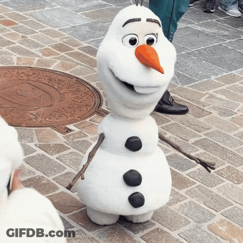 A Snowman Is Standing On A Brick Sidewalk And Smiling GIF