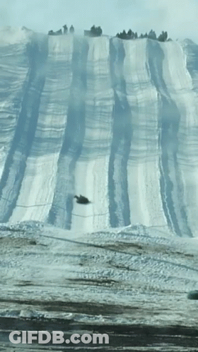 A Snowmobile Going Down A Snowy Hill GIF