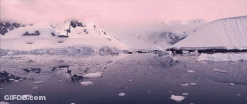 A Snowy Landscape With Mountains And Ice In The Water GIF