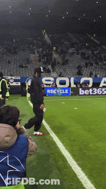 A Soccer Field With A Solo Recycle Sign In The Background GIF