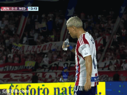A Soccer Player Holds A Bottle Of Water In Front Of A Sign That Says Fosforo Natural GIF