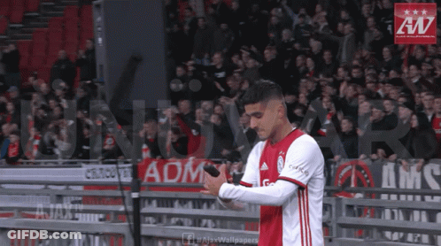A Soccer Player Holds A Microphone In Front Of A Banner That Says Ajax Wallpaper GIF