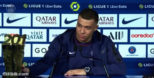 A Soccer Player Holds A Trophy In Front Of A Qatar Airways Advertisement GIF