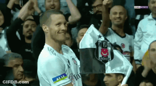 A Soccer Player Holds Up A Flag With A Shield On It GIF