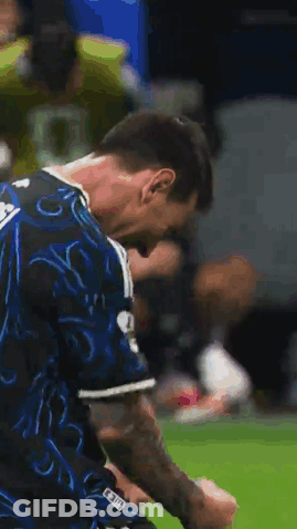 A Soccer Player In A Blue And Black Jersey Is Standing On A Field . GIF