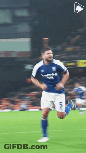 A Soccer Player In A Blue And White Uniform Is Running On A Field . GIF