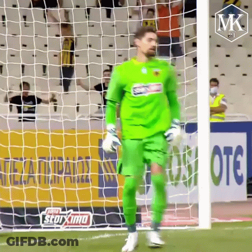 A Soccer Player In A Green Uniform Is Standing In Front Of A Net GIF