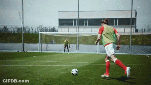 A Soccer Player In A Green Vest Kicks A Soccer Ball GIF