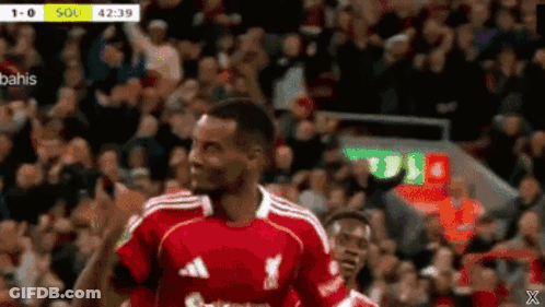 A Soccer Player In A Red Adidas Jersey Stands In Front Of A Crowd . GIF