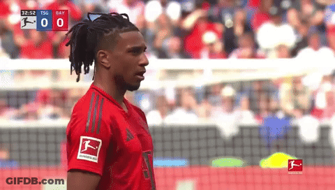 A Soccer Player In A Red Adidas Jersey Stands In Front Of A Scoreboard GIF