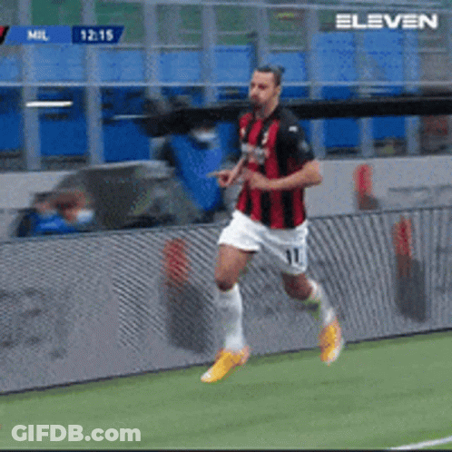 A Soccer Player In A Red And Black Jersey Is Running On A Field GIF