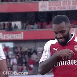 A Soccer Player In A Red Emirates Jersey Is Standing On A Field . GIF