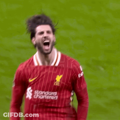 A Soccer Player In A Red Jersey Is Kicking A Ball On A Soccer Field . GIF