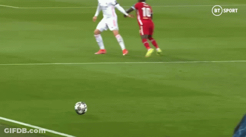 A Soccer Player In A Red Jersey Is Kicking A Soccer Ball While Another Player Tries To Stop Him . GIF