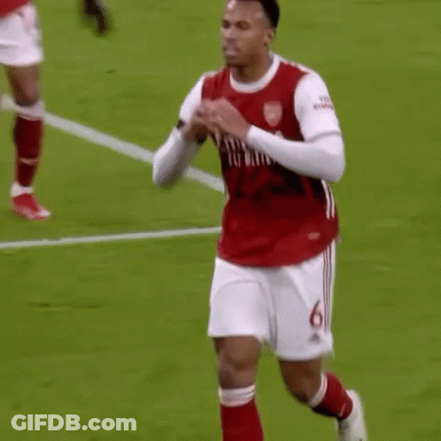 A Soccer Player In A Red Shirt And White Shorts Is Running On A Field . GIF