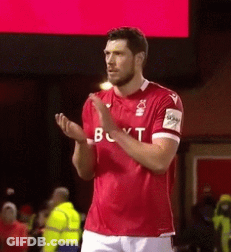 A Soccer Player In A Red Shirt Is Applauding The Crowd . GIF