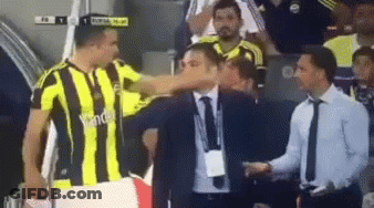 A Soccer Player In A Yellow And Black Striped Shirt Is Shaking Hands With A Man In A Suit GIF