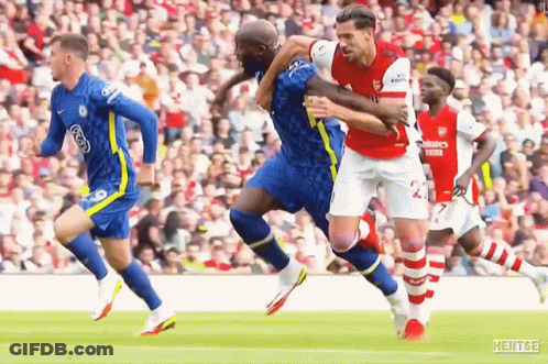 A Soccer Player Is Being Tackled By Another Player During A Game . GIF
