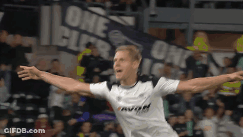 A Soccer Player Is Celebrating A Goal In Front Of A Banner That Says One GIF