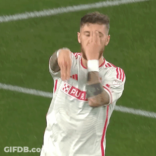 A Soccer Player Is Covering His Face With His Hands While Wearing A White Jersey With Red Stripes GIF