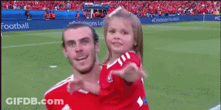 A Soccer Player Is Holding A Little Girl On His Shoulders On A Field . GIF