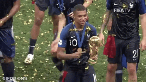 A Soccer Player Is Holding A Trophy And A Medal While His Teammates Celebrate . GIF