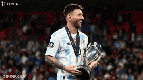 A Soccer Player Is Holding A Trophy And Smiling With A Typito Logo In The Background GIF