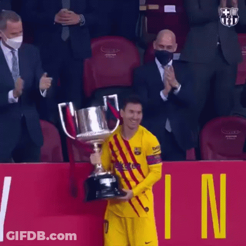 A Soccer Player Is Holding A Trophy In Front Of A Crowd While Wearing A Mask . GIF