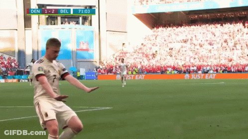 A Soccer Player Is Kicking A Ball On A Field With A Just Eat Banner In The Background GIF